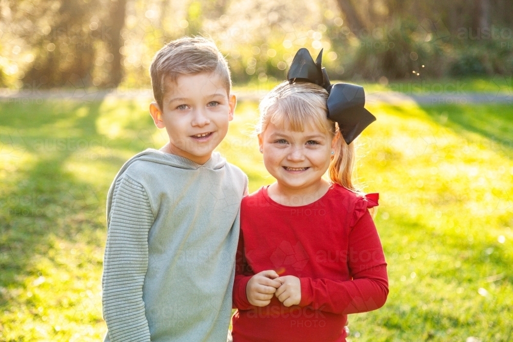 Image of Brother and sister smiling together in golden light - Austockphoto