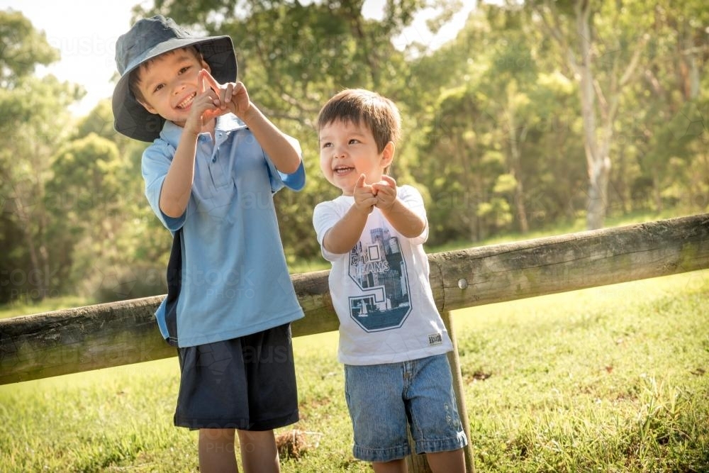 Brothers play together outside in the park after school - Australian Stock Image