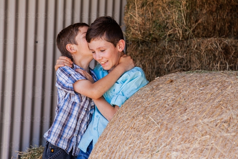 Brothers playing together in hay shed - Australian Stock Image