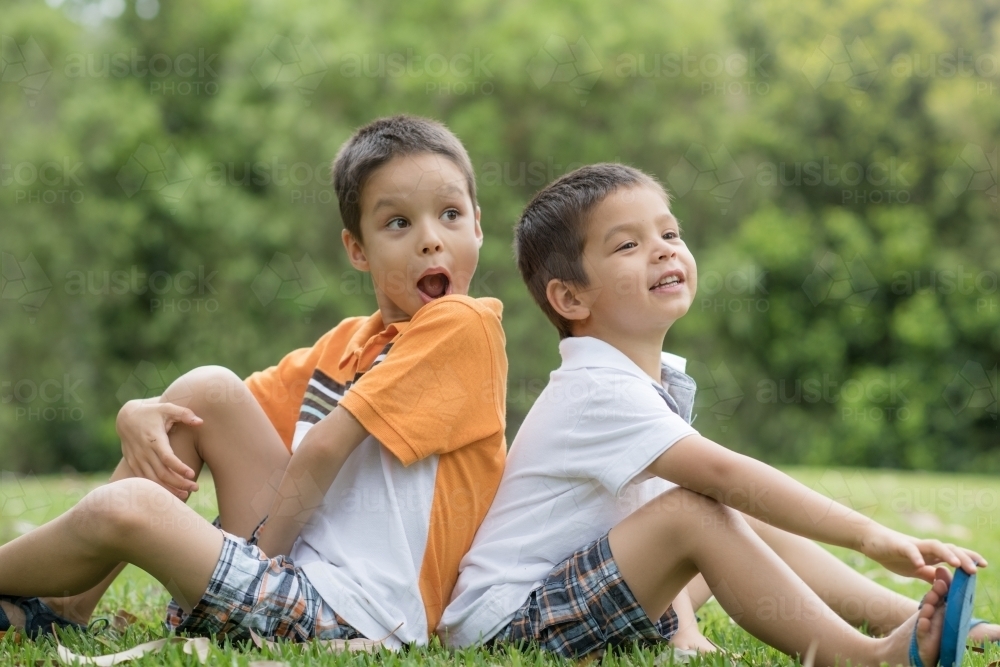 Brothers sit back to back outside - Australian Stock Image