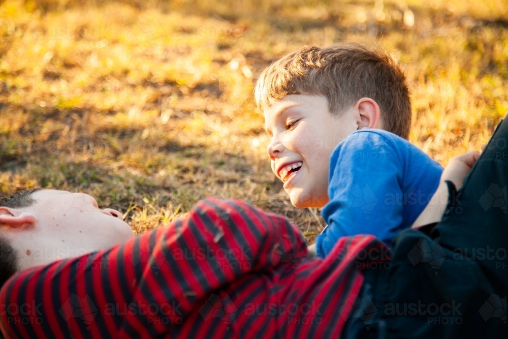 Brothers tackle wrestling each other outside - Australian Stock Image