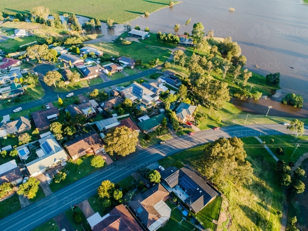 Brown floodwaters backflowing over farmland flooding towards houses - Australian Stock Image