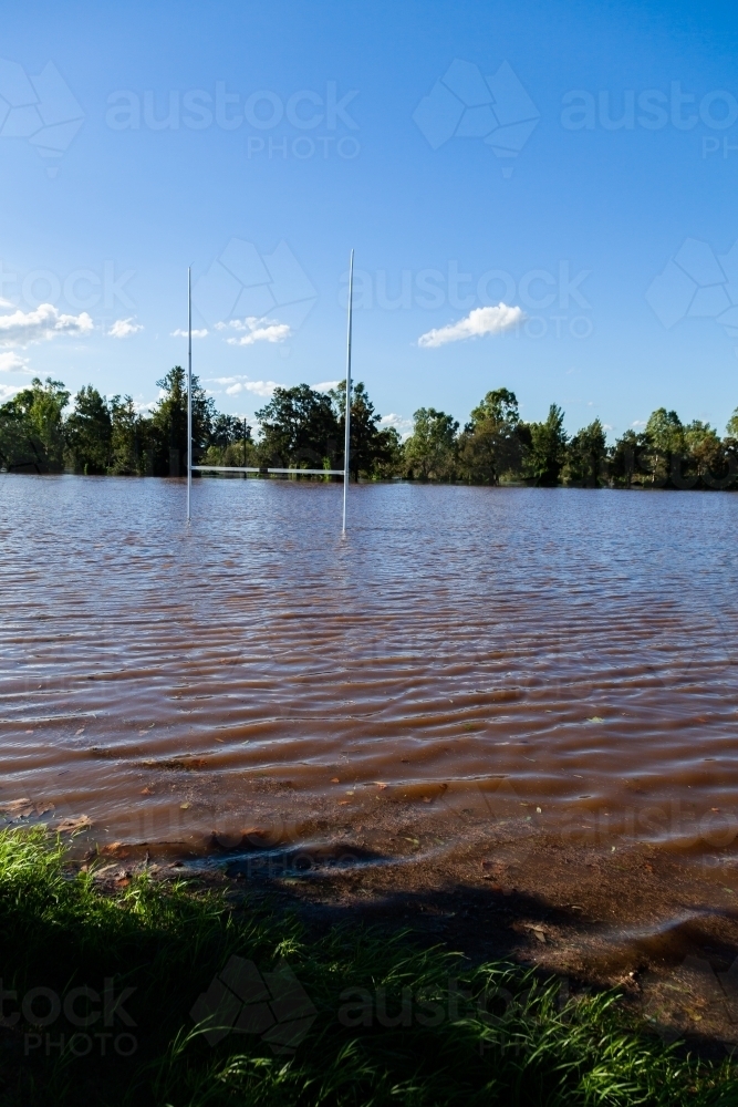 Brown floodwaters covering park playing field after river broke banks - Australian Stock Image