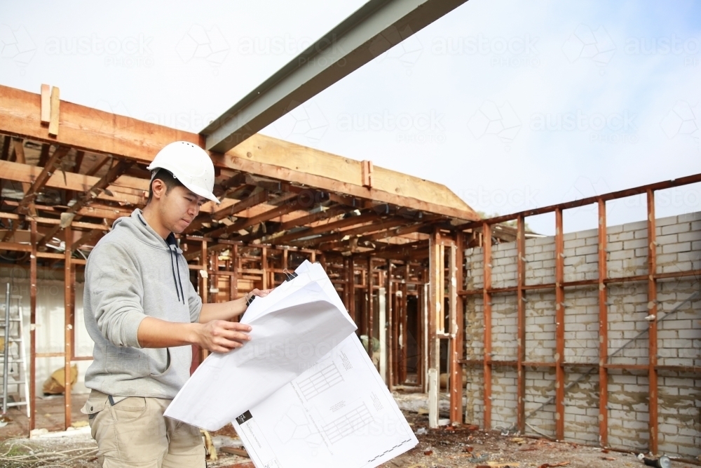 Builder checking construction plans on-site - Australian Stock Image