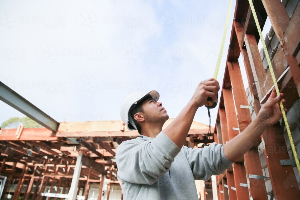 Builders Using Measure Image of Builder measuring construction framework - Austockphoto