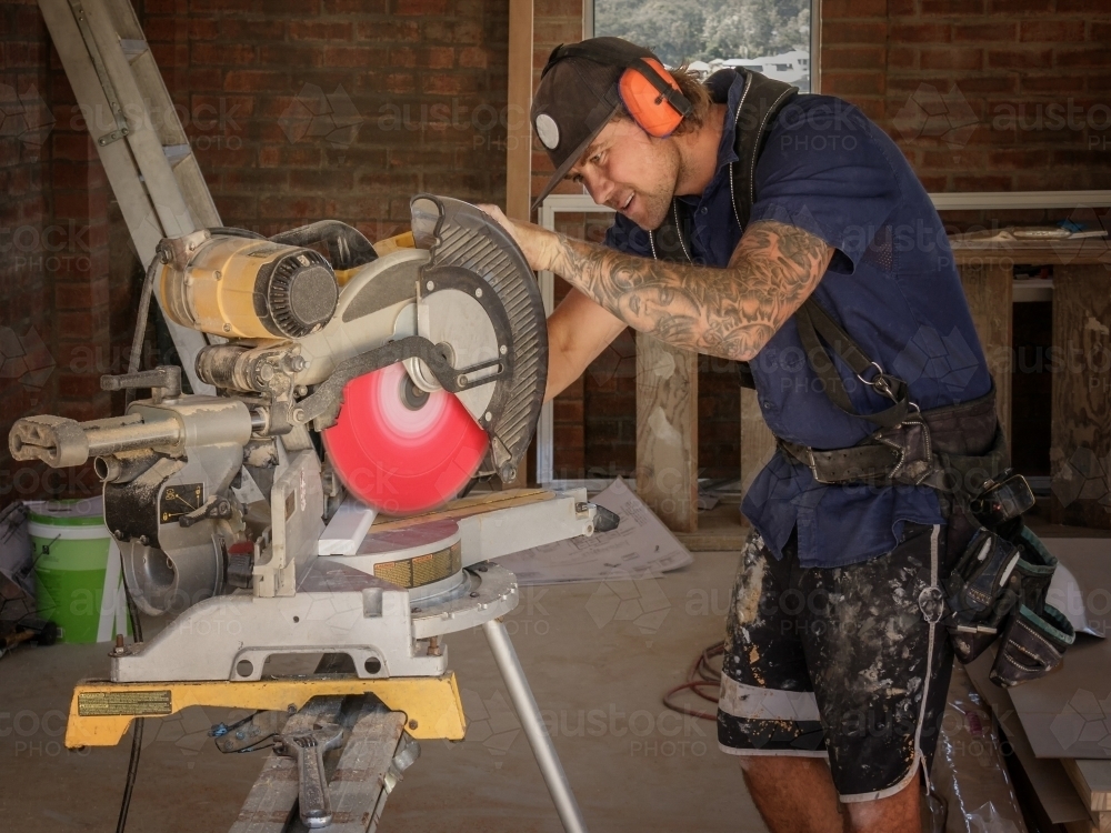 Builder using drop saw on timber at residential construction site - Australian Stock Image