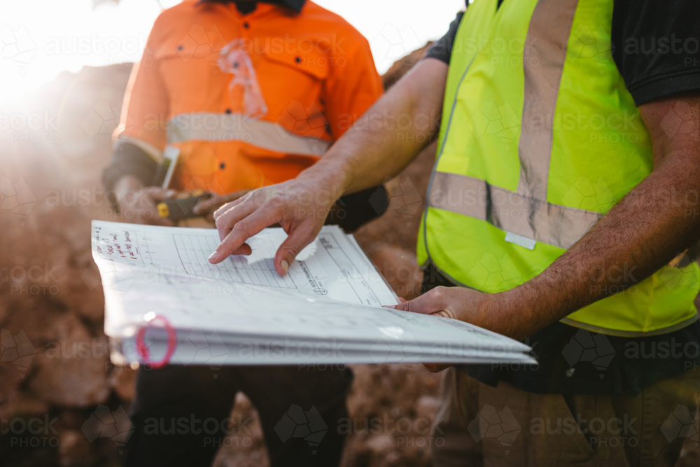 Image of Builders pointing at the blueprint at the construction site ...