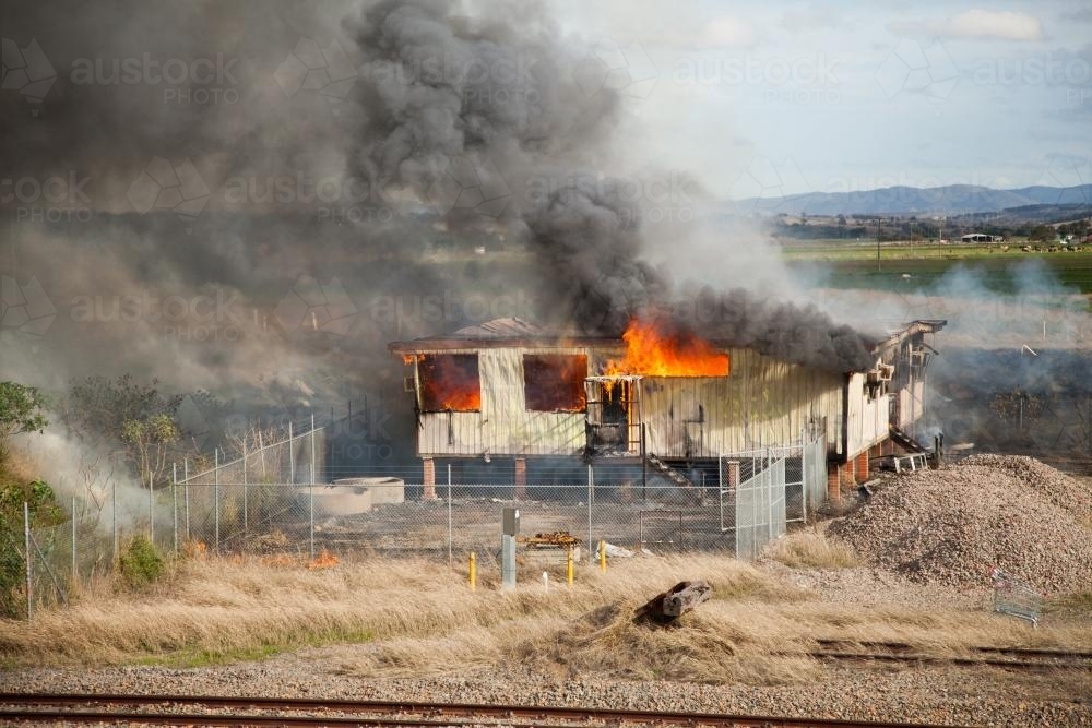 Burning shed belching black smoke into the bright day - Australian Stock Image
