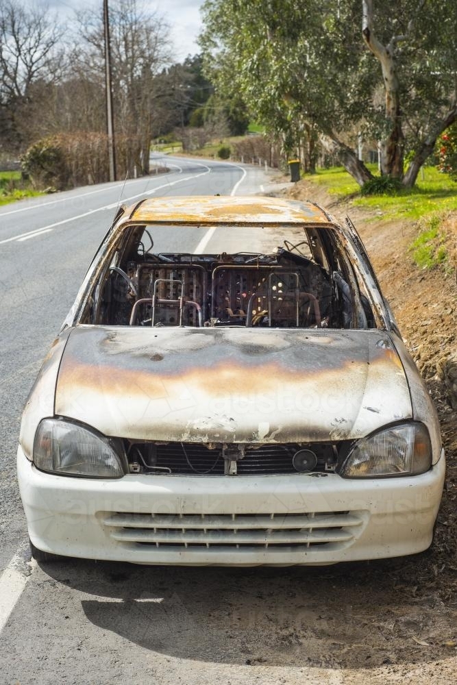 burnt out stolen car abandonded on the roadside - Australian Stock Image