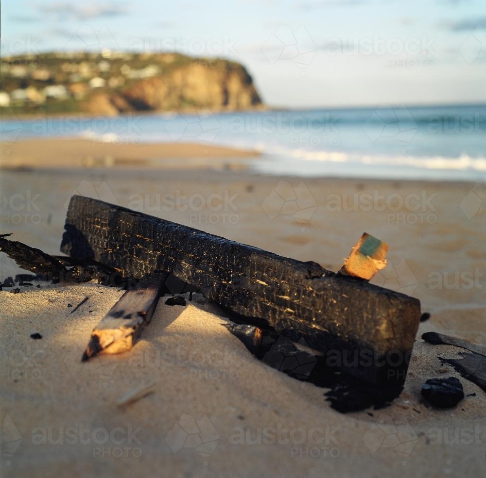 Burnt wood on a beach - Australian Stock Image