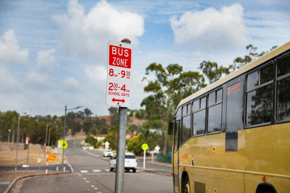 Bus zone street sign with yellow school bus beside it - Australian Stock Image