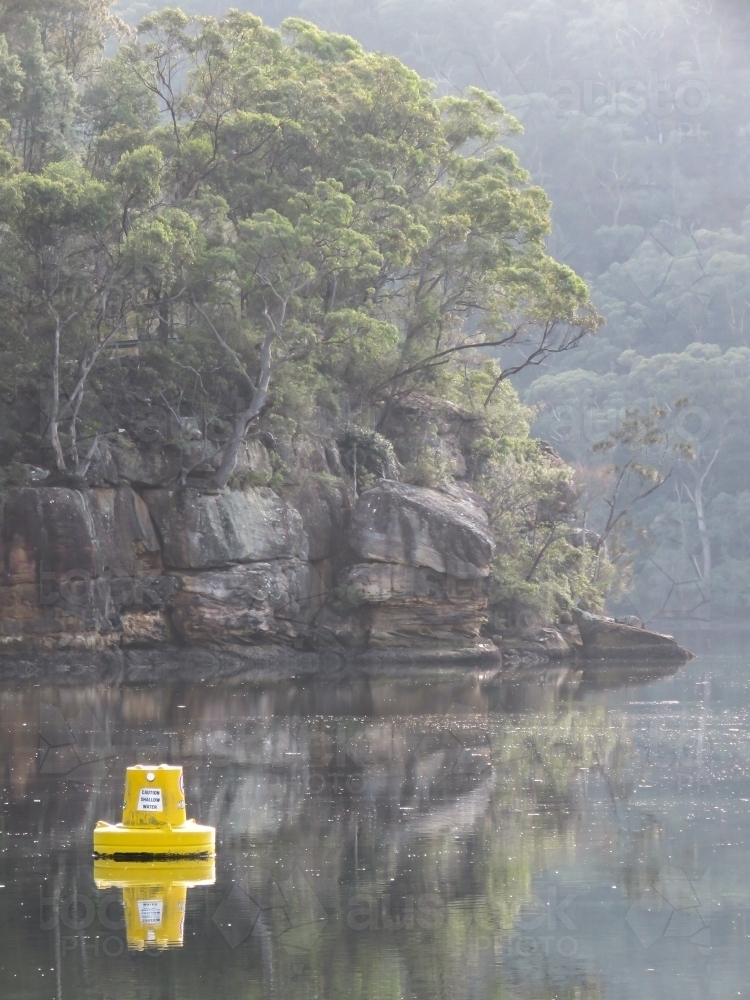 Bush and early morning mist on still water, with a navigation buoy - Australian Stock Image