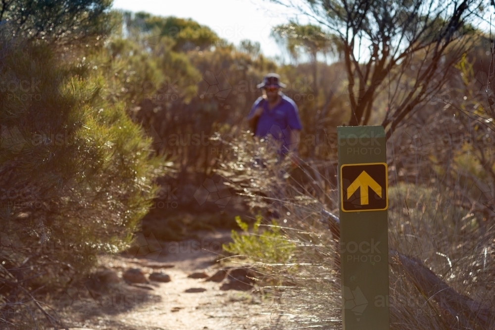 bush walking trail marker with person in background - Australian Stock Image