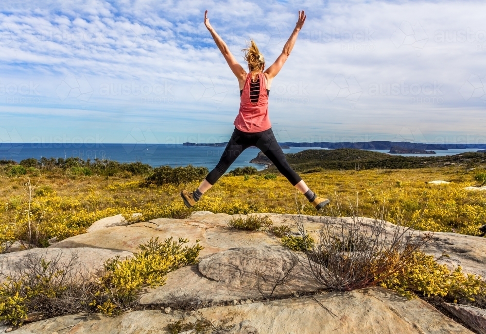 Bushwalking along coastal headlands filled with flowering wildflowers in spring - Australian Stock Image