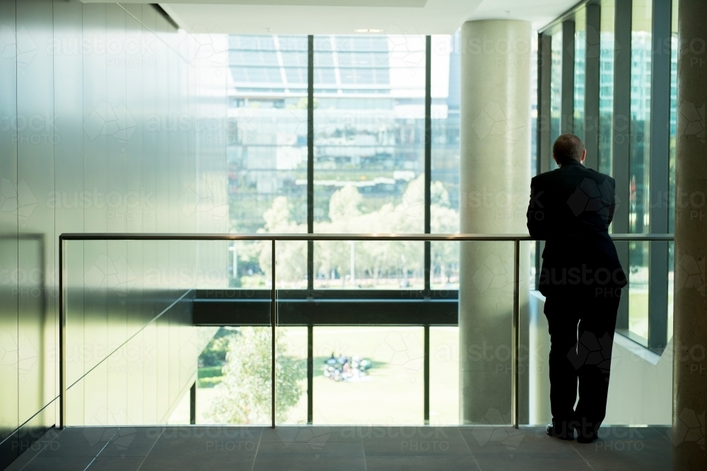Business man leaning on office balcony - Australian Stock Image