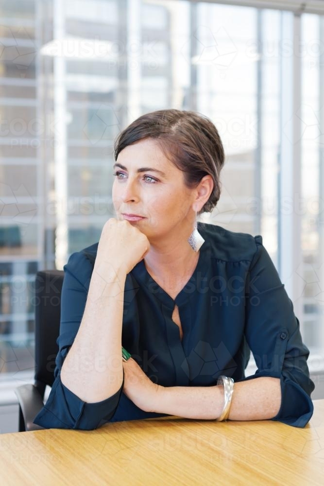 Business woman sitting at a boardroom table - Australian Stock Image