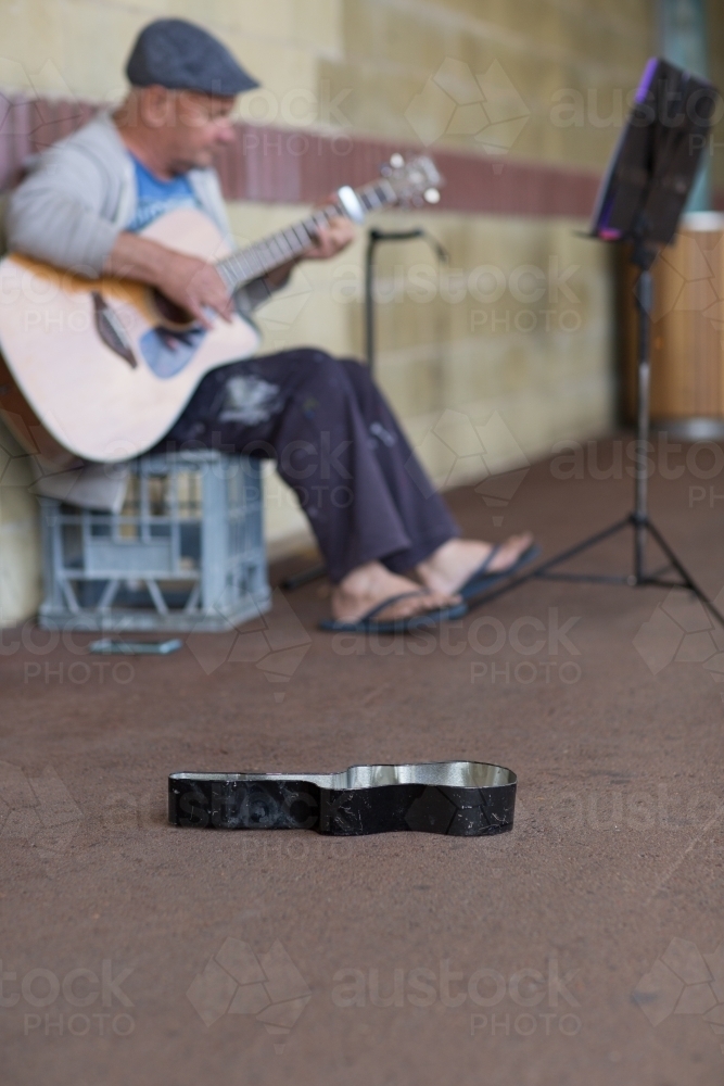 Busker sitting on milk crate playing guitar - Australian Stock Image