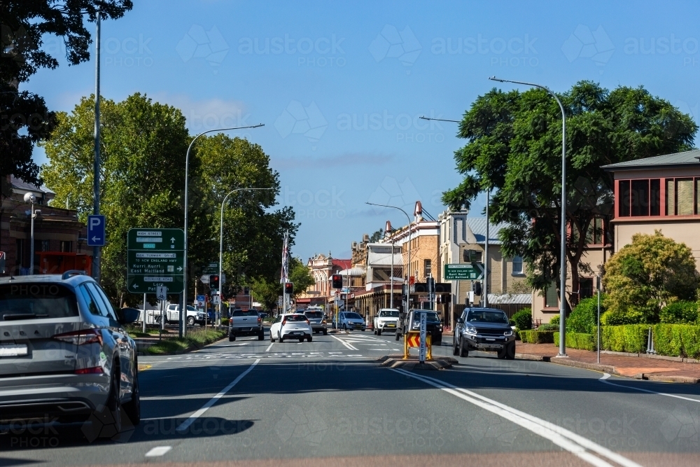 Busy street in town with old buildings beside road shot from passenger seat - Australian Stock Image