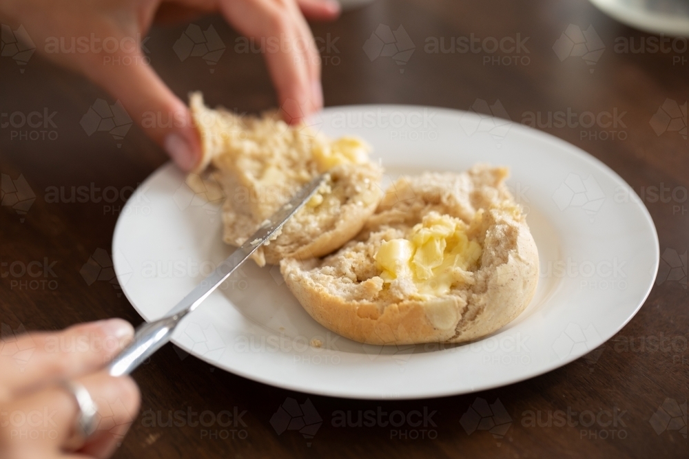 buttering a homemade bun or a white plate - Australian Stock Image