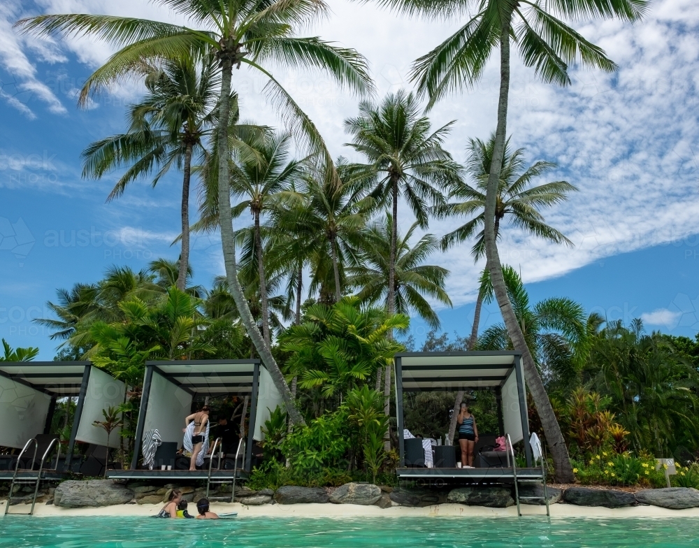cabanas surrounded by coconut trees at a beach resort - Australian Stock Image