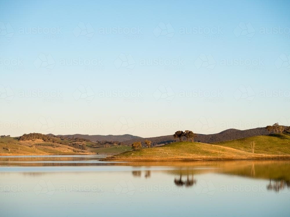 Calm regional dam with reflected hills and trees - Australian Stock Image