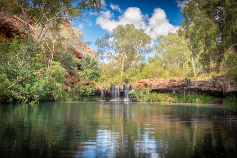Calm waters and a clear reflection in front of the Karijiini waterfall - Australian Stock Image