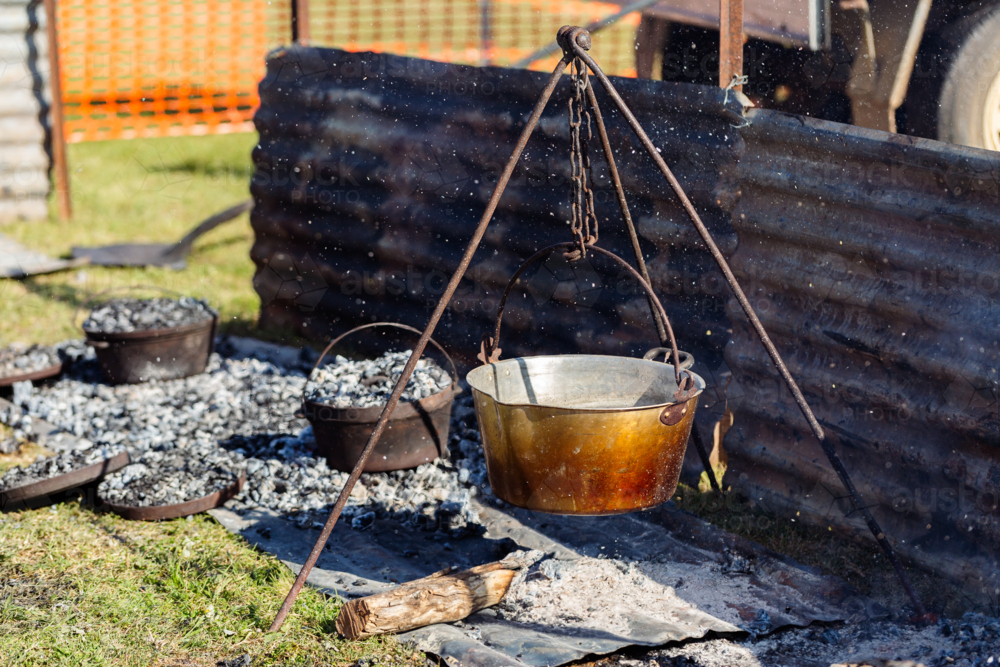 camp oven cooking damper bread on fire coals shielded by corrugated iron - Australian Stock Image