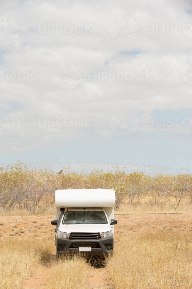 Camper van driving in dry grassland - Australian Stock Image