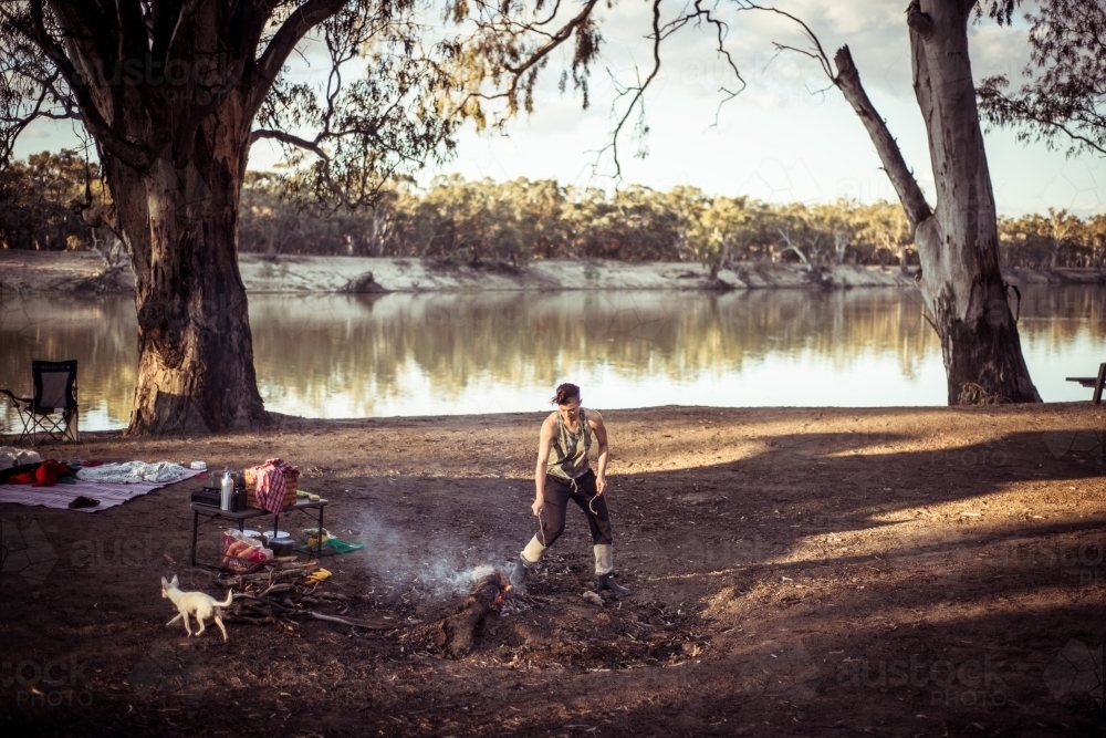 Camping life - woman by the campfire the river - Australian Stock Image