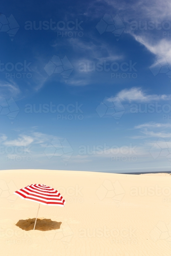 Candy stripe beach umbrella on a sand dune - Australian Stock Image