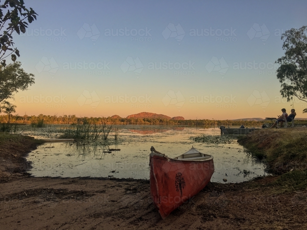 Canoe beside lake at sunset - Australian Stock Image