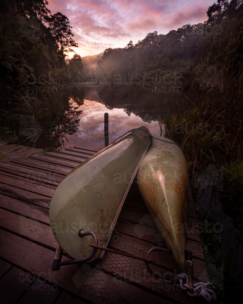 Canoes docked at a Rainforest Lake at Sunrise - Australian Stock Image