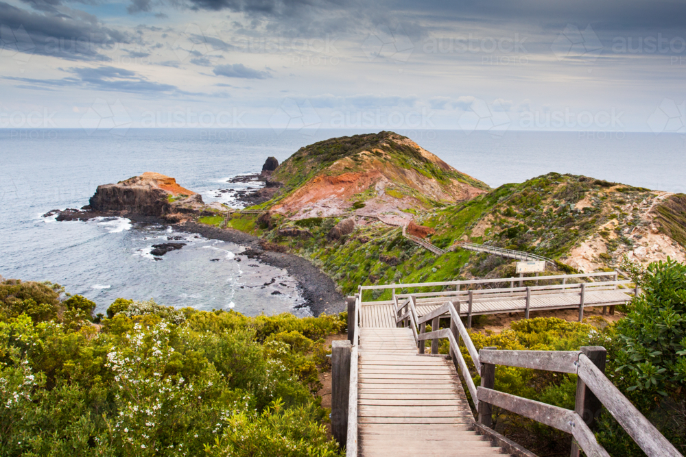 Cape Schanck boardwalk runs towards the sea and rock formation known as London Bridge - Australian Stock Image