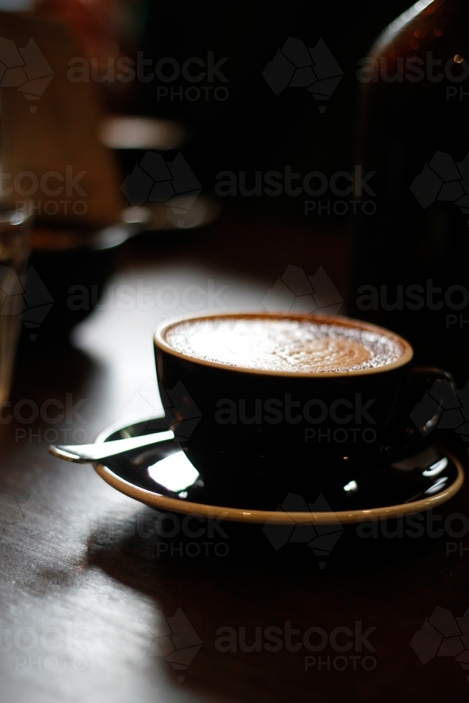 Cappuccino in a ceramic cup on a dark wooden surface - Australian Stock Image