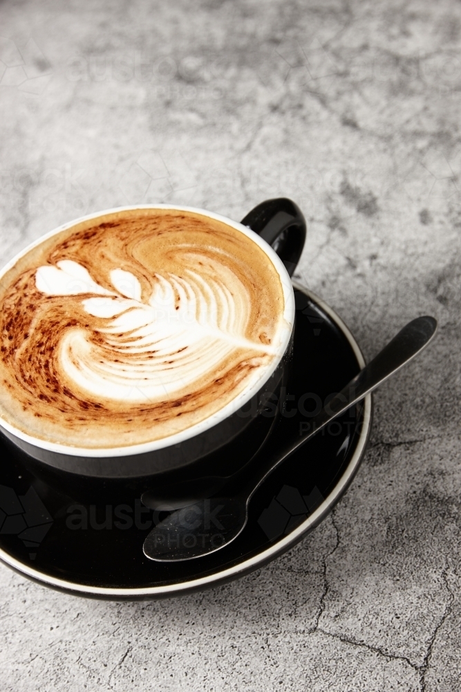 Cappuccino on black saucer - Australian Stock Image
