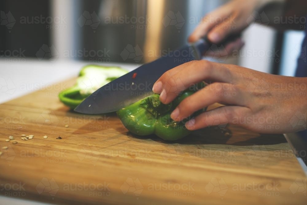 Capsicum being cut on a cutting board - Australian Stock Image