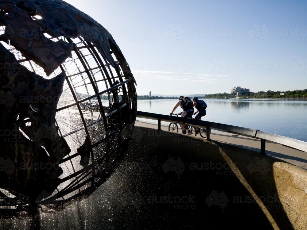 Captain Cook Memorial Globe with two cyclists and Lake Burley Griffin - Australian Stock Image