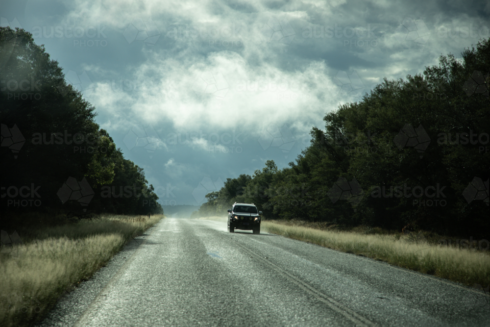 Car driving on a tree lined, bitumen road - Australian Stock Image