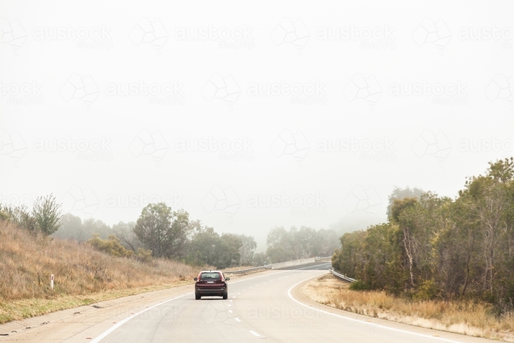 Car driving on road in hazardous condition fog - Australian Stock Image