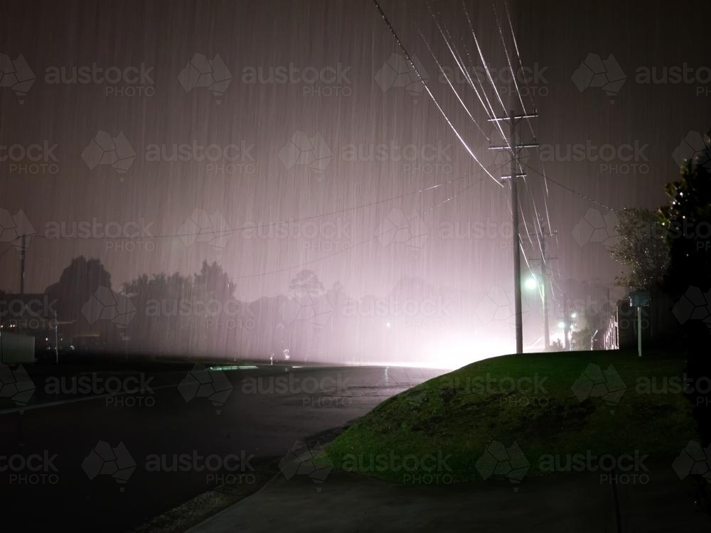 Car headlights reflecting on power lines and pouring rain - Australian Stock Image