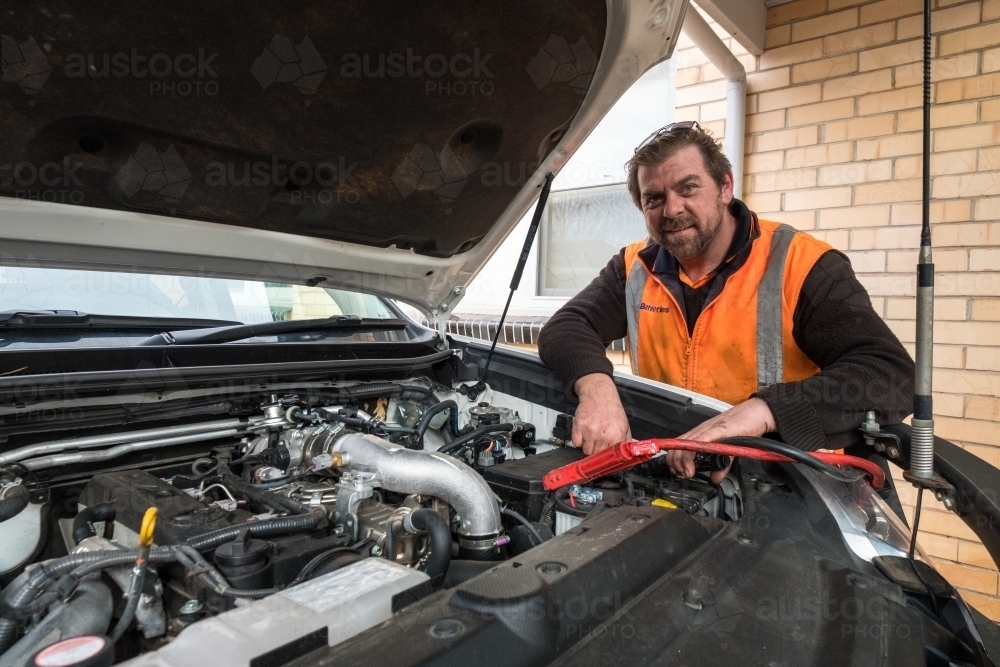 Image of Car mechanic jumpstarting car with flat battery Austockphoto