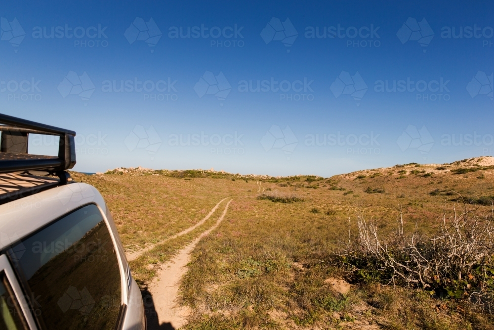 Car on four wheel drive trail in sand dunes under blue sky - Australian Stock Image