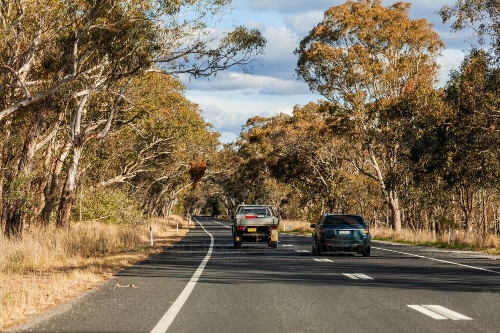 Car overtaking ute on country road with dotted lines - Australian Stock Image