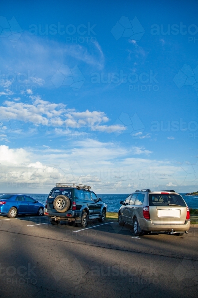 Car parked over the lines in coastal car park with large sky - Australian Stock Image