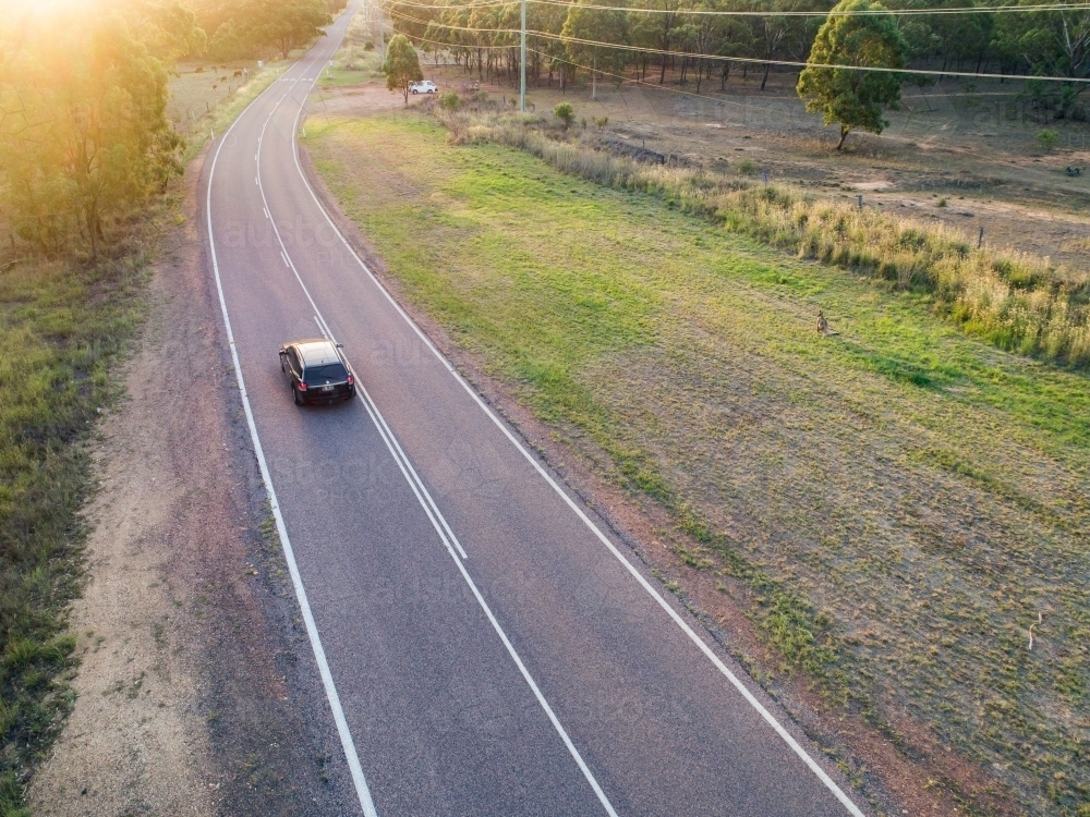 Image of Car traveling down country road at sunset Austockphoto