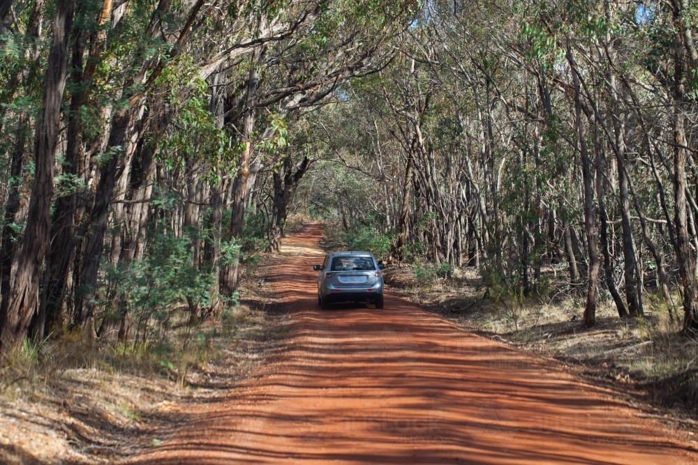 Image of Car travelling on red dirt road Austockphoto