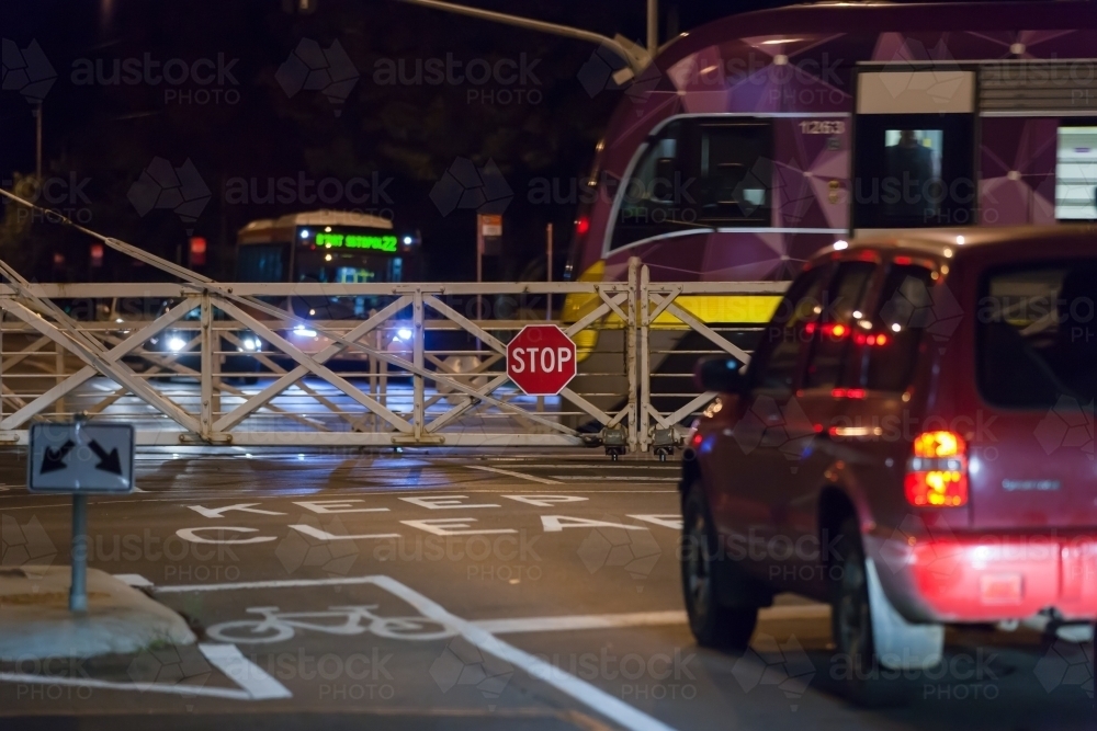 car waiting at rail crossing with train passing through - Australian Stock Image