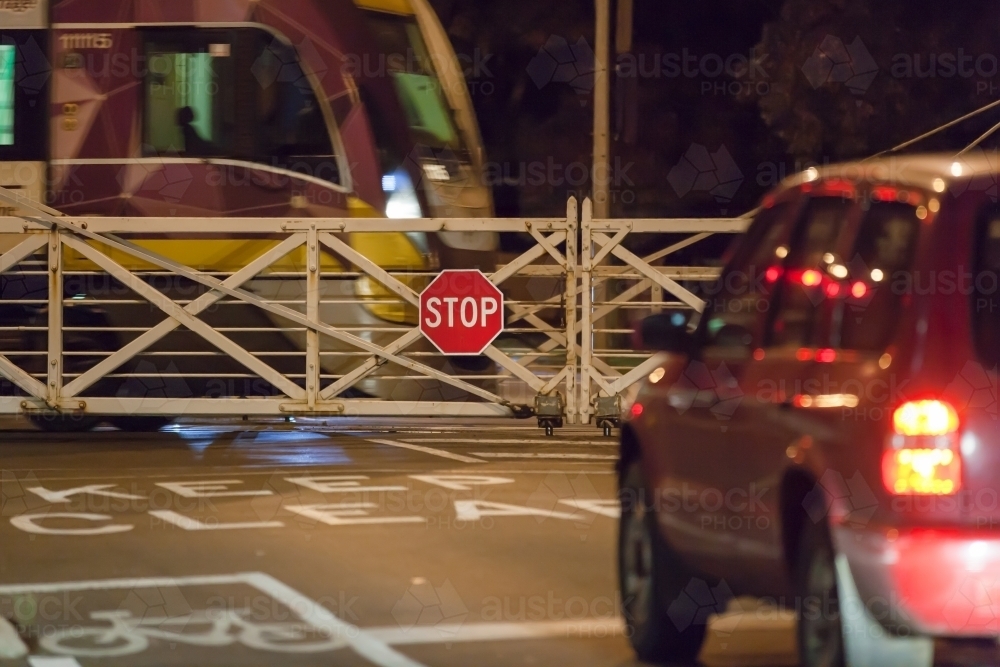 car waiting at rail crossing with train passing through - Australian Stock Image