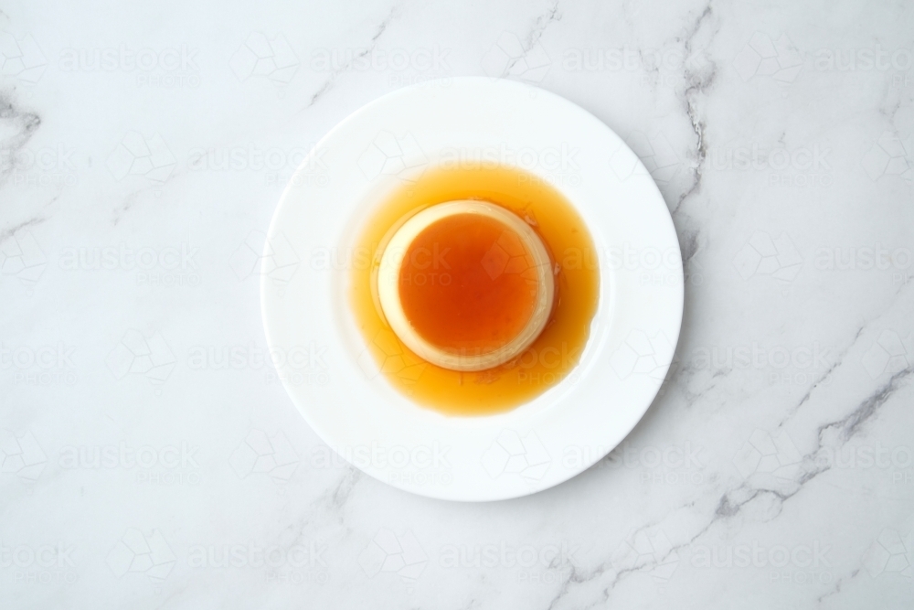 Caramel pudding plate on marble surface - Australian Stock Image