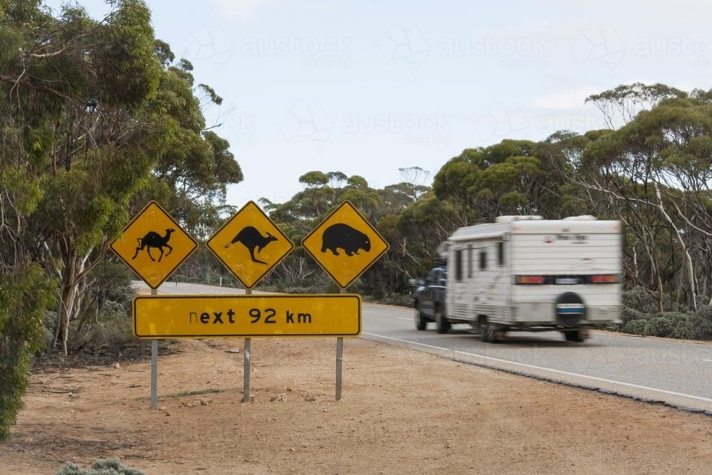 Caravan driving across the nullarbor past road signage - Australian Stock Image